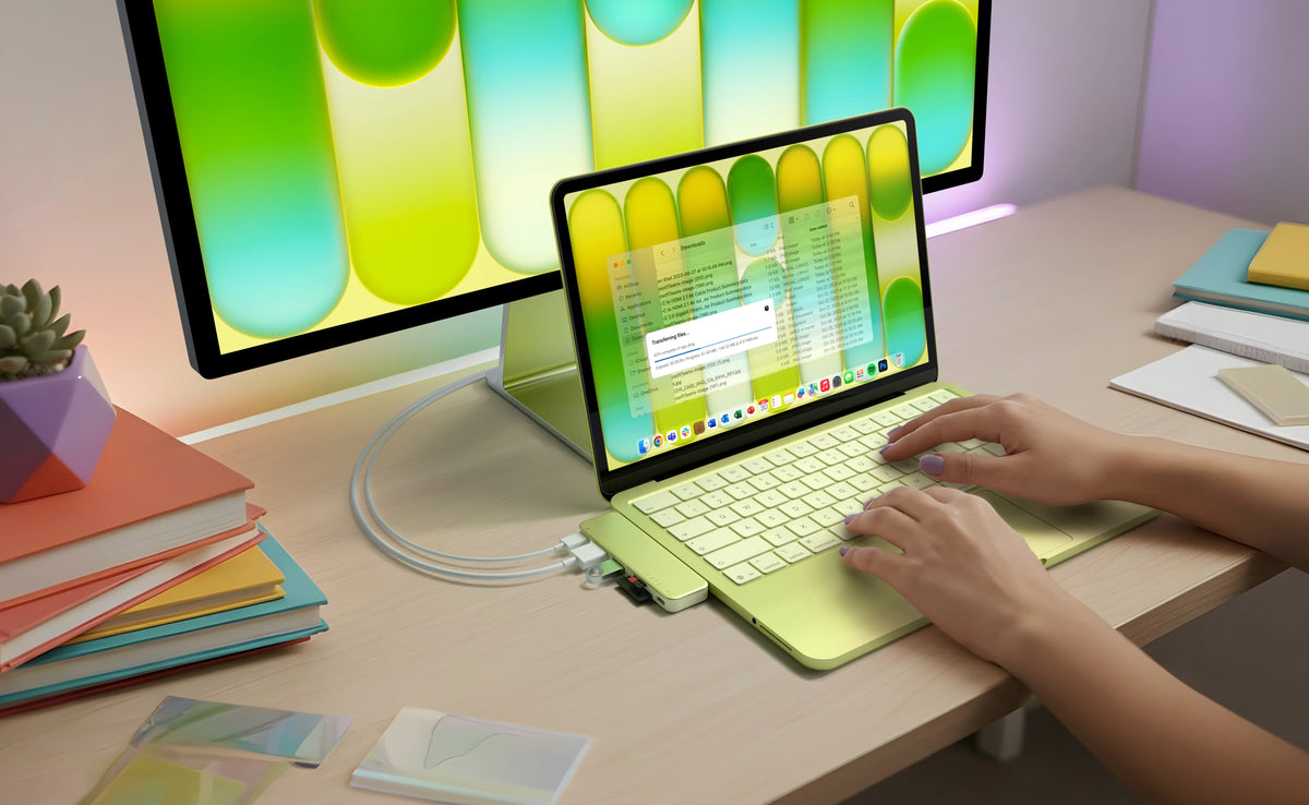 A Citrus MacBook Neo with a matching Satechi USB-C Snap Hub in Citrus attached and displaying onto second external iMac monitor.