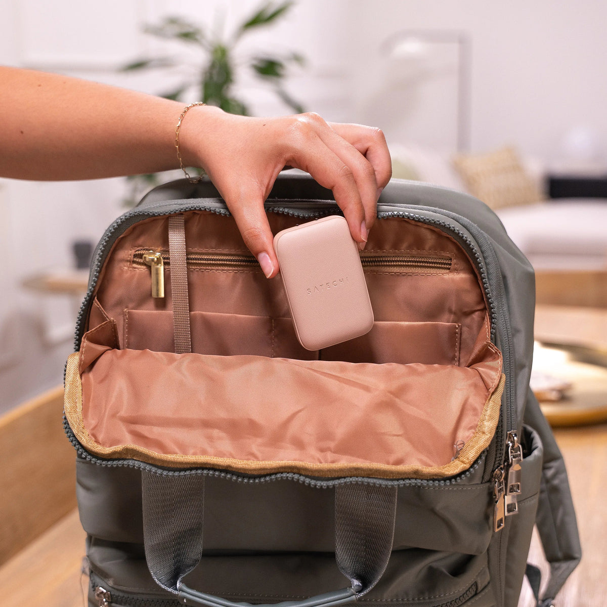 A hand putting a Satechi OntheGo™ 67W Slim Wall Charger into a backpack.