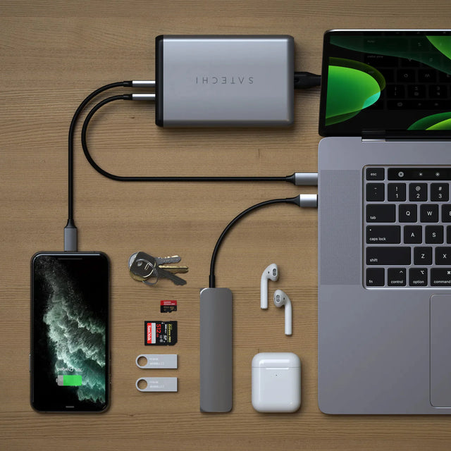 Satechi 108W Pro USB-C PD Desktop Charger charging  electronic devices like iPhone and MacBook on a wooden surface.