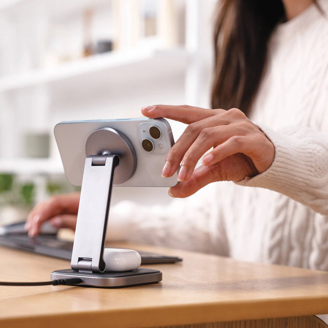 Person using a 2-in-1 Foldable Qi2 Wireless Charging Stand with an iPhone on a desk.