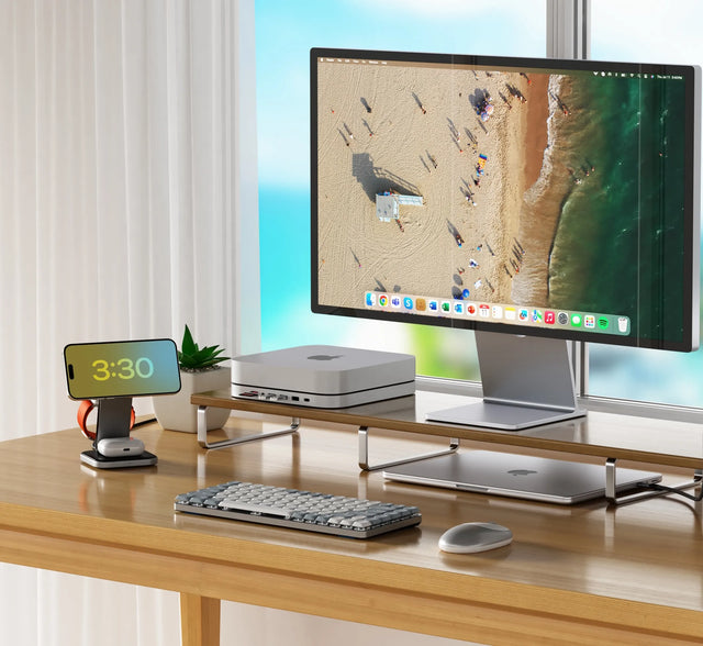 Modern office desk setup with computer monitor, keyboard, mouse, and Satechi 3-in-1 Foldable Qi2 Wireless Charging Stand  charging iPhone, AirPods, and Apple Watch on a wooden desk.
