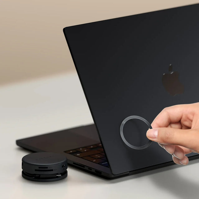 Person holding the  OntheGo™ 7-in-1 Multiport Adapter's magnetic ring to show the ability to magnetically attach to compatible portable devices. 