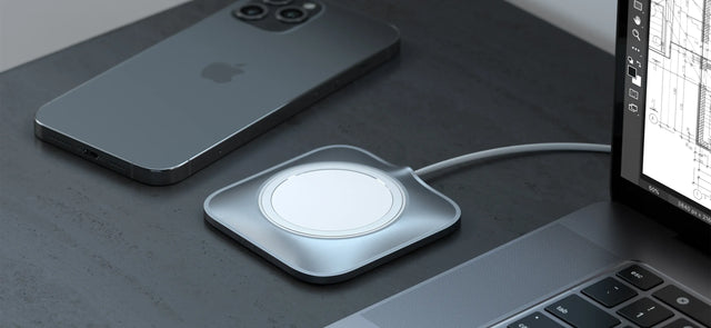 A Satechi Aluminum Dock for MagSafe Charger laying nearby an iPhone and a MacBook. 