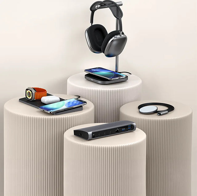 Satechi Trio Wireless Charger with Magnetic Pad, Thunderbolt 4 Dock, 2-in-1 Headphone Stand with Wireless Charger, and USB-C Magnetic Wireless Charging Cable displayed on neutral pedestal stands charging two iPhones, an Apple Watch, a pair of AirPods, and headphones. 