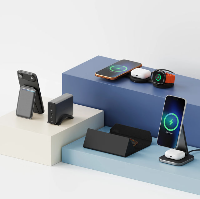 A collection of Satechi products set on elevated display platforms, featuring OntheGo™ 3-in-1 Charger charging an iPhone, Apple Watch, and AirPods, 2-in-1 Foldable Qi2 Wireless Charging Stand charging an iPhone and AirPods, Vegan-Leather FindAll™ Glasses Case, an iPhone attached to a Vegan-Leather Magnetic Wallet Stand, and a 165W USB-C 4-Port PD GaN Charger.
