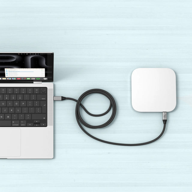 Satechi USB4 V2 Pro Cable linking a laptop to a compact USB‑C hub on a light blue desk, demonstrating stable high‑speed connectivity for accessories.
