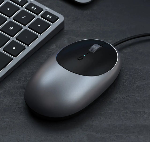 Close‑up of the Satechi C1 USB‑C Wired Mouse next to a keyboard, highlighting its ergonomic shape and modern aluminum design.