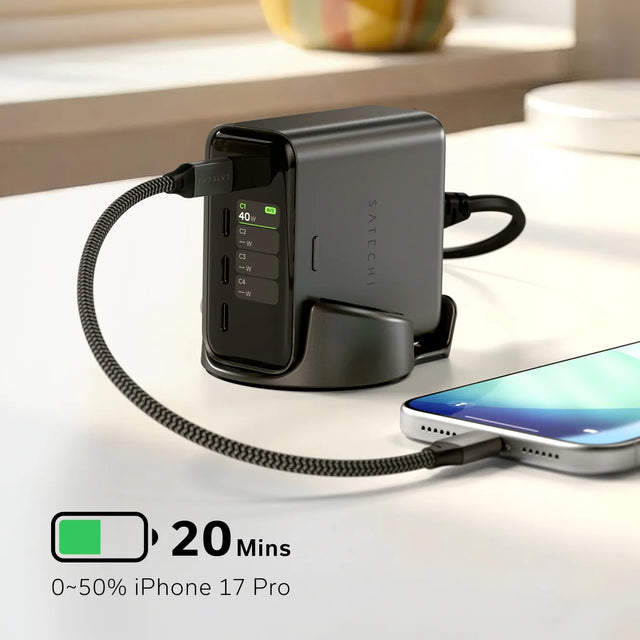 Satechi ChargeView™ 140W Desktop Charger on a white desk, shown upright in a charging stand with a connected smartphone and braided USB‑C cable. The front display shows port status with visible labels “C1 40W,” “C2,” “C3,” and “C4.” On-image text reads “20 Mins” next to a battery icon and “0~50% iPhone 17 Pro.” The compact gray desktop charger provides high‑power fast charging for multiple devices in a modern workspace setting.