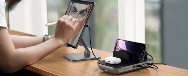Person using a stylus on a tablet with an iPad being charged by the Satechi Dock5 Multi-Device Charging Station, while charging AirPods and iPhone at same time. 