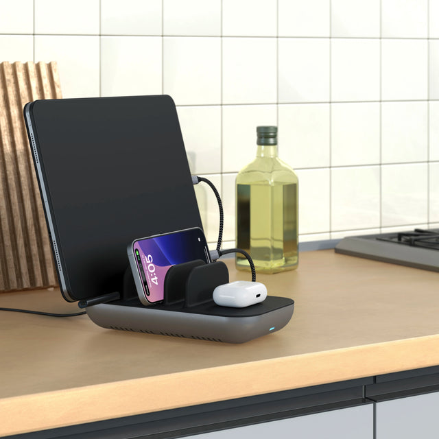 The Satechi Dock5 Multi-Device Charging Station in a kitchen counter with iPhone , AirPods, and iPad. 