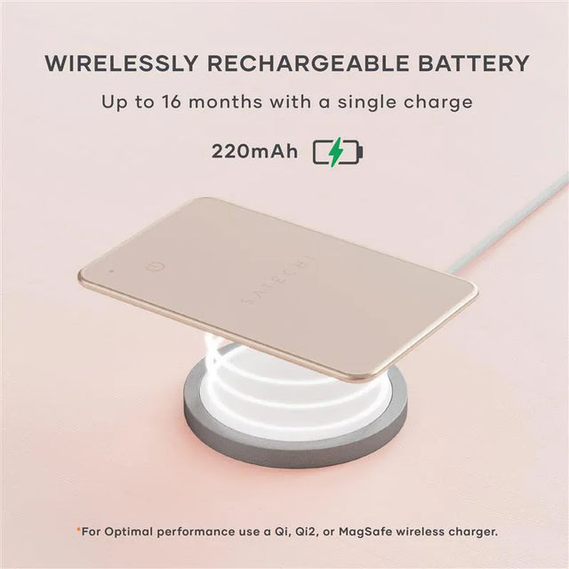 Satechi FindAll Card charging wirelessly on a Qi‑compatible charging pad, highlighting its long‑lasting rechargeable battery. A charging icon floats above.  Text says " WIRELESSLY RECHARGEABLE BATTERY
Up to 16 months with a single charge
220mAh. *For Optimal performance use a Qi, Qi2, or MagSafe wireless charger."