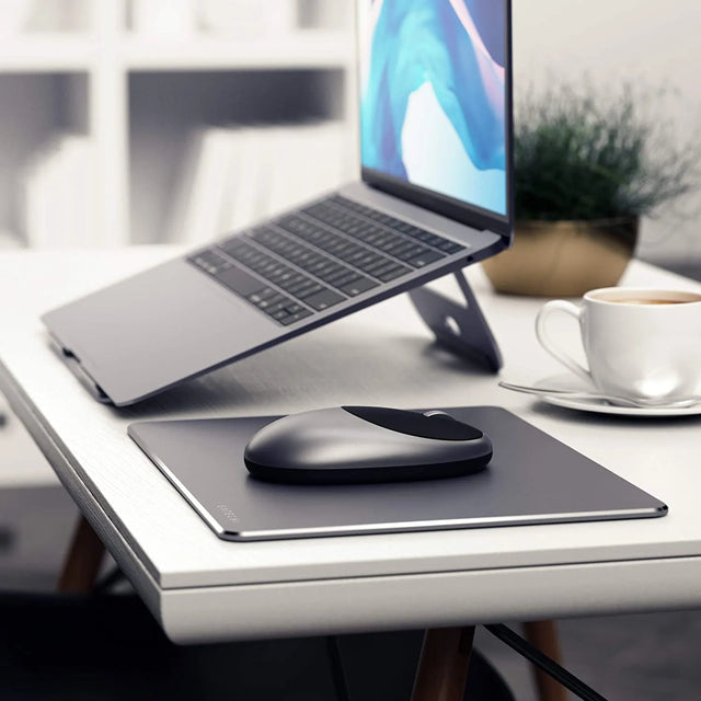  M1 Wireless Mouse placed on a matching mouse pad beside a laptop on a clean workspace with a cup of coffee.