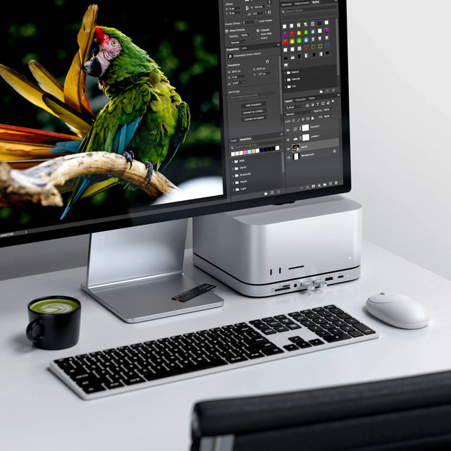 Modern desk setup with Satechi Stand & Hub For Mac Mini / Studio With NVMe SSD Enclosure attached to a Mac Studio, connected to 
monitor, Slim X3 Bluetooth Backlit Keyboard, wireless M1 mouse, and a cup of coffee.