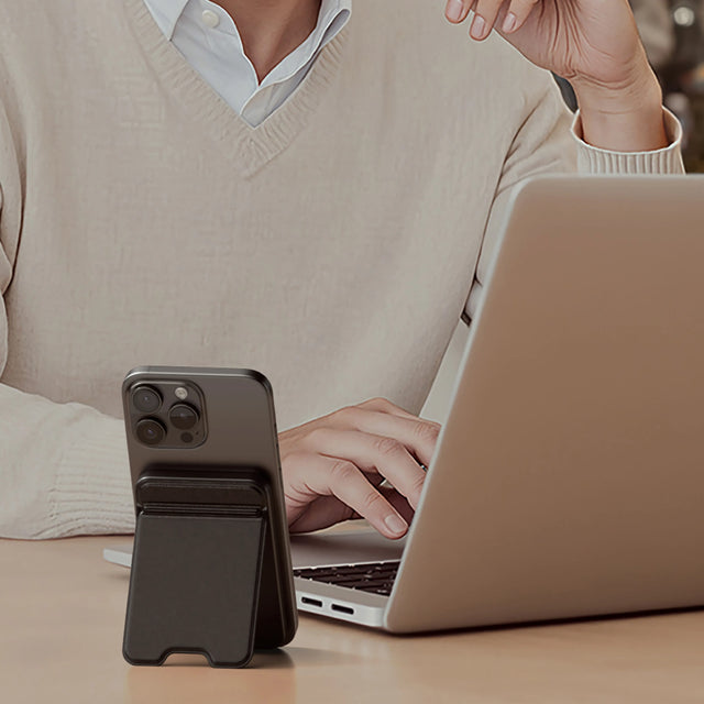 Satechi OntheGo Power Bank 5K holding a iPhone upright beside a laptop, showing its magnetic stand design for hands‑free use while working.