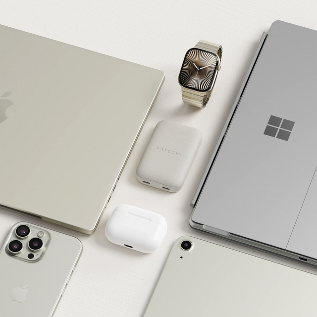 The OntheGo™ 67W Slim Wall Charger in the middle of a flat lay of a collection of Apple and Microsoft electronic devices on a white surface.