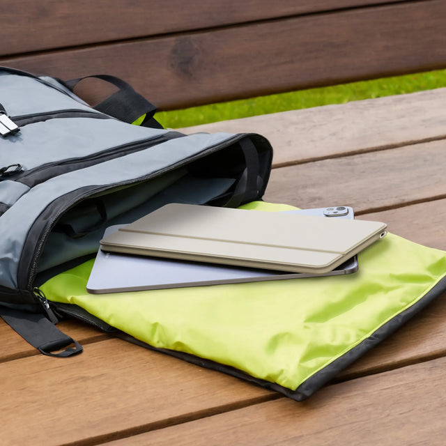 Gray backpack with green interior lining on a wooden surface with OntheGo™ Bluetooth Keyboard with Stand folded ontop. 