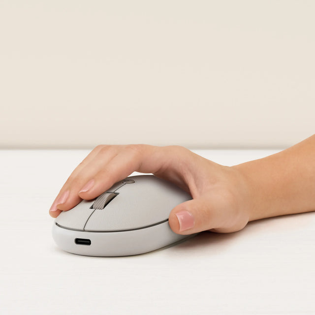 Hand holding an OntheGo™ Bluetooth Mouse on a light surface with a neutral background.