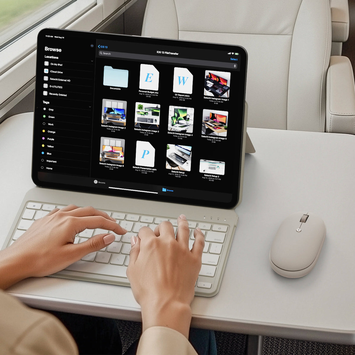 A person uses a sand wireless keyboard and OntheGo™ Bluetooth Mouse in sand with a tablet on a white desk. The tablet screen shows a web interface, and the person's hands are visible typing on the keyboard.
