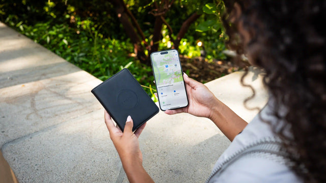 A person holding a Vegan-Leather FindAll™ Passport Cover while an iPhone is actively tracking with Apple Find My technology.  
