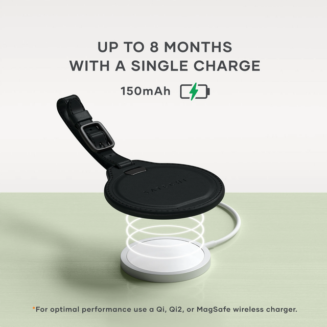 Black Satechi Vegan‑Leather FindAll Luggage Tag charging wirelessly on a Qi-compatible charging pad. A charging icon floats nearby. Text says "UP TO 8 MONTHS
WITH A SINGLE CHARGE
150mAh. For optimal performance use a Qi, Qi2, or MagSafe wireless charger." 