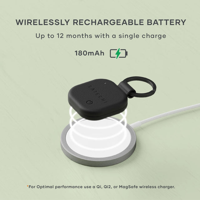 Black Satechi Vegan‑Leather FindAll Keychain charging wirelessly on a Qi-compatible charging pad. A charging icon floats above. Text says " WIRELESSLY RECHARGEABLE BATTERY
Up to 12 months with a single charge
180mAh. *For Optimal performance use a Qi, Qi2, or MagSafe wireless charger." 