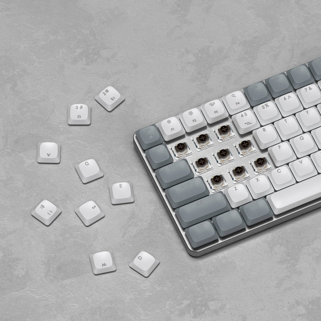 SM1 Slim Mechanical Backlit Bluetooth Keyboard with several keycaps removed to reveal hot‑swappable mechanical switches on a gray textured surface.