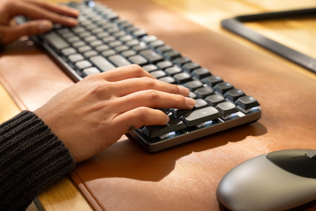 Person typing on a SM3 Slim Mechanical Backlit Bluetooth Keyboard with  adjustable feet for optimum efficiency and comfort.