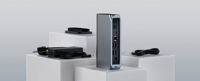 A Thunderbolt 4 Multimedia Pro Dock on a white platform against a light gray background, showing its stand, power source and thunderbolt cable. 