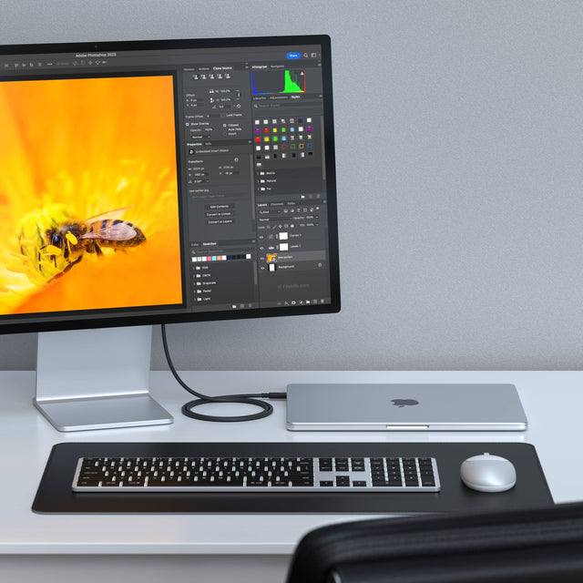 Modern office desk setup with computer monitor connected via a Thunderbolt 4 Pro Cable to a MacBook, while Slim X3 keyboard and M1 mouse sit nearby.