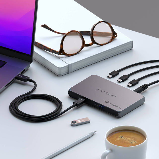 A close-up of the The Thunderbolt 4 Slim Hub, featuring 3x Thunderbolt 4 ports, 1x USB-A port, and 1x upstream Thunderbolt 4 port. Thunderbolt 4 Slim Hub is charging a MacBook.