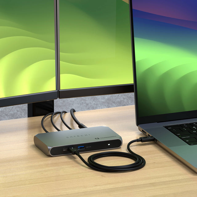 Close-up of a Thunderbolt 4 Slim Hub Pro connected to a MacBook via a Thunderbolt 4 cable, displaying two external monitors.