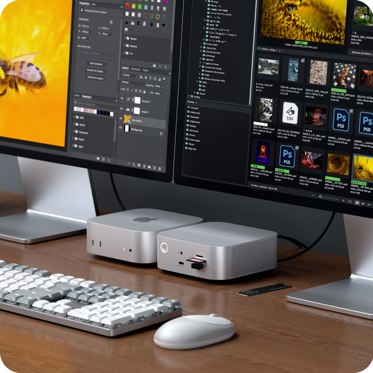 A Satechi Thunderbolt 5 CubeDock™ with SSD Enclosure and Mac Mini M4 connected to two iMac monitors displaying software interfaces, a keyboard, and a mouse on a wooden desk.