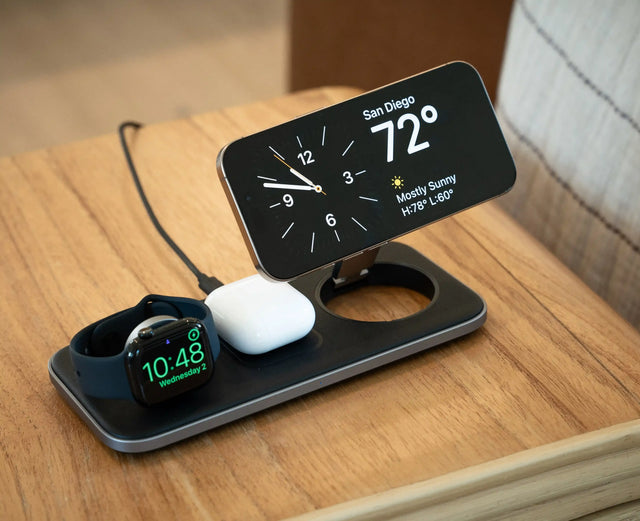 Satechi Qi2 Trio Wireless Charging Pad charging an iPhone, Apple Watch, and AirPods on top of a coffee table. 