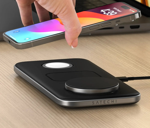 A hand placing an iPhone on the Satechi Qi2 Trio Wireless Charging Pad.