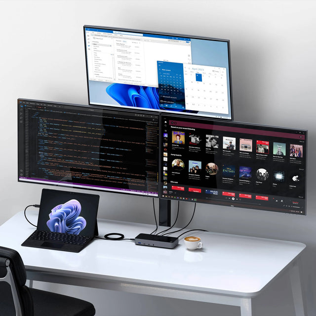 Satechi Triple 4K display Docking Station connected to a laptop on a modern white desk, powering three external monitors that show productivity apps, code, and media content, demonstrating multi‑screen workstation capabilities.