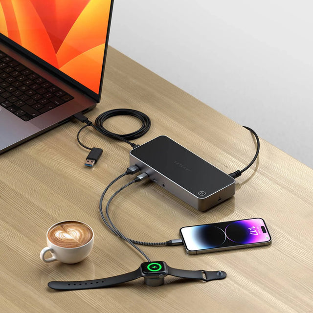 Triple 4K Display Docking Station on a wooden desk connected to a MacBook, charging an iPhone and Apple Watch through multiple ports, showcasing its multi‑device power and connectivity features.