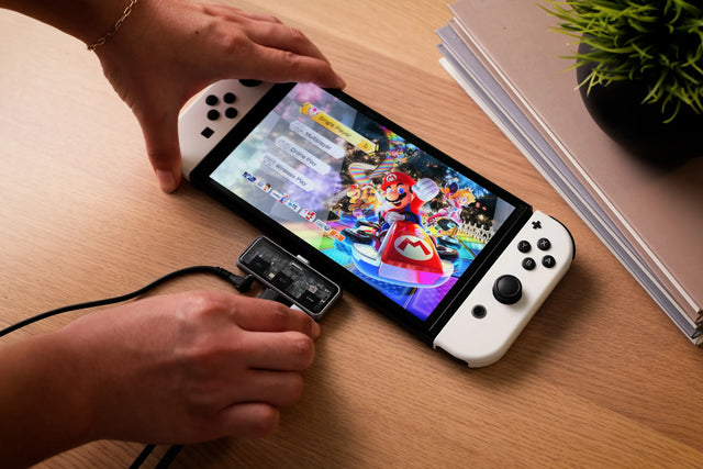 Person plugging a cable into a Satechi Mobile XR Hub with microSD Reader
 that is connected to a Nintendo Switch console displaying a game.